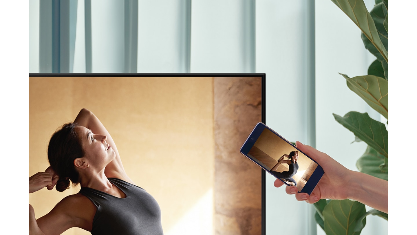 Người dùng chạm điện thoại thông minh của mình vào TV AU8000 để phản chiếu nội dung múa ba lê lên màn hình lớn hơn để có trải nghiệm xem thoải mái hơn.